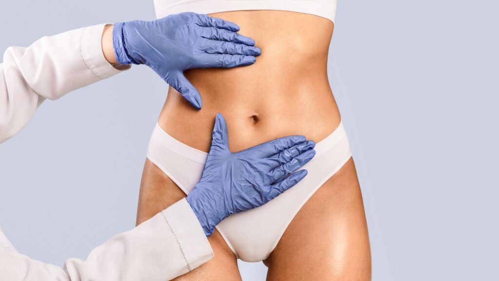 Woman having liposuction treatment at dr stanwix plastic surgery, doctor examining belly