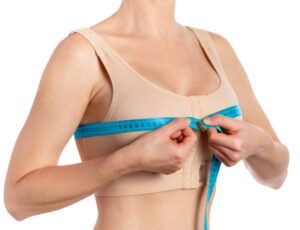 Woman taking measurements after breast augmentation isolated on white background with clipping path.